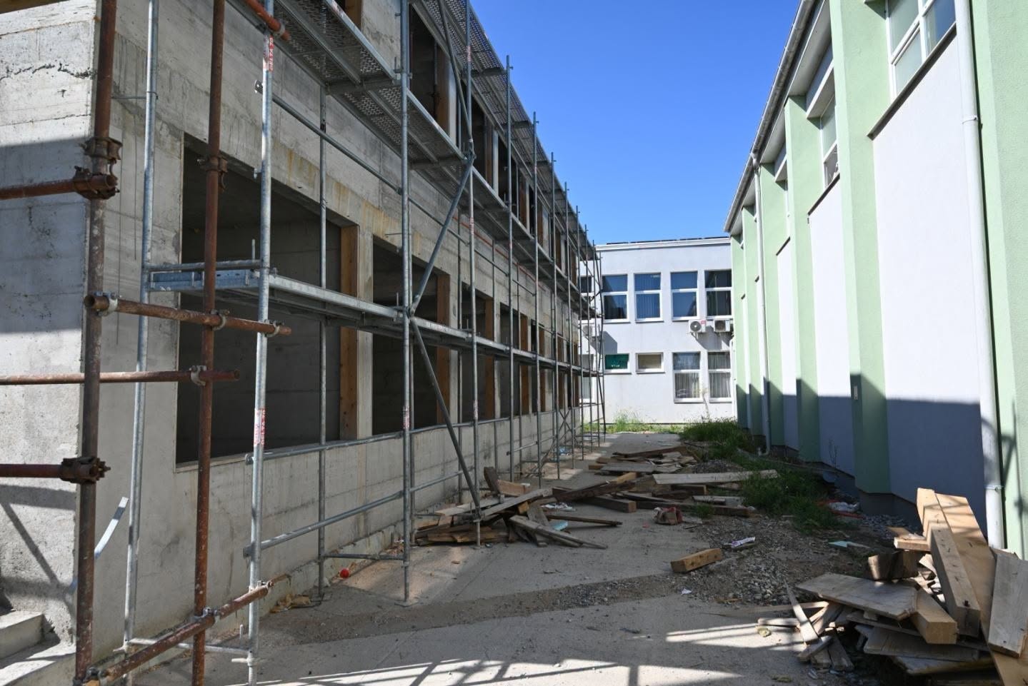 Gradilište s metalnom skelom uz betonsku konstrukciju zgrade.