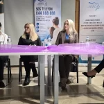 Četiri sudionice tribine sjede za stolom ispred panoa Centra za žene Adela.