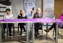Četiri sudionice tribine sjede za stolom ispred panoa Centra za žene Adela.