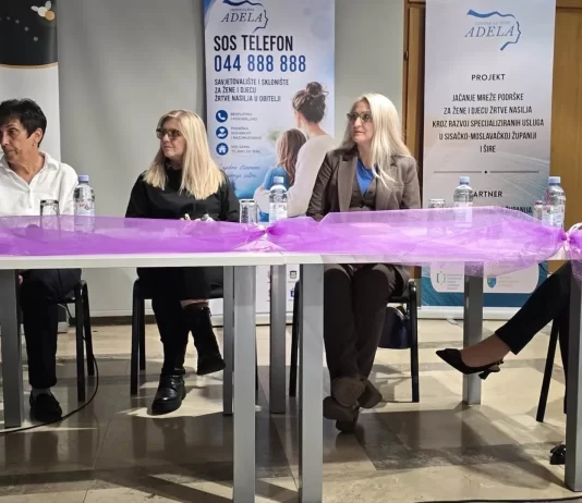 Četiri sudionice tribine sjede za stolom ispred panoa Centra za žene Adela.