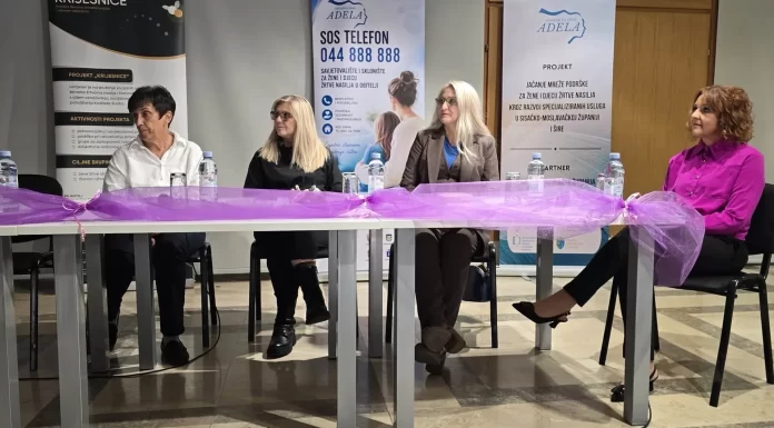Četiri sudionice tribine sjede za stolom ispred panoa Centra za žene Adela.